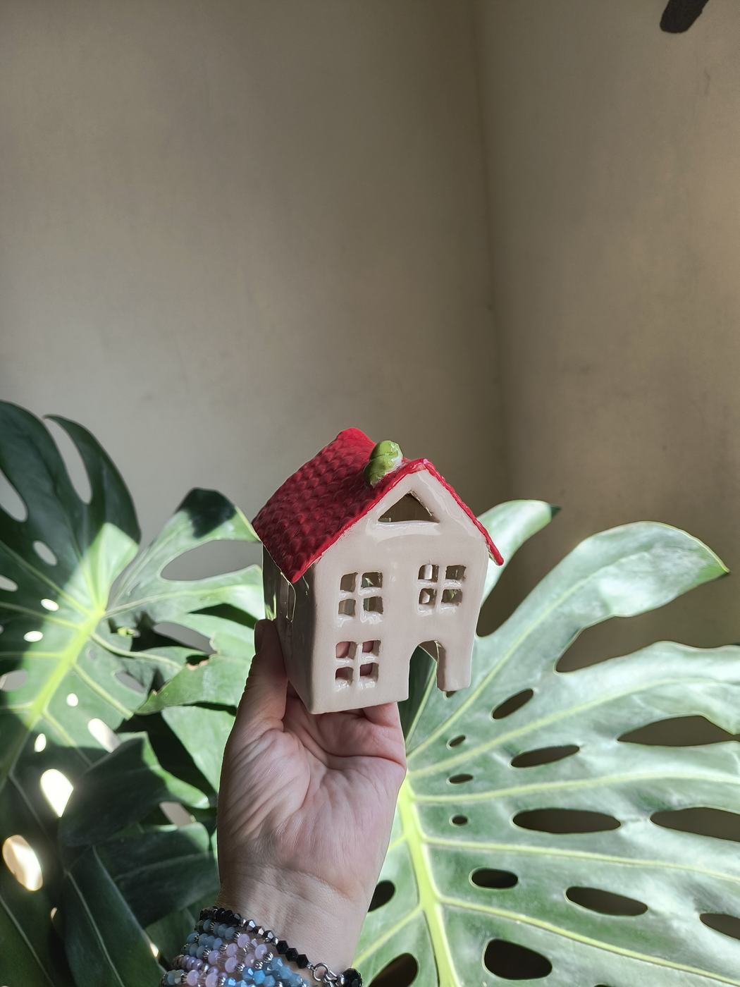 Una casita de cerámica con techo rojo y ventanitas caladas